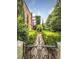 View of the garden through a black wrought iron gate and leading to a brick building with greenery at 309 Meeting St # 19, Charleston, SC 29401
