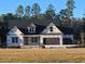 New construction home displaying modern architectural style with a dark roof, bright white trim, and an attached two-car garage at 313 Tack House Rd, Huger, SC 29450
