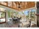 Inviting screened porch with wood ceiling, a dining table, fireplace and outdoor seating with views of the marsh at 4 Falcon Point Rd, Kiawah Island, SC 29455