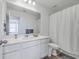 Bright bathroom with gray geometric shower curtain, white sink cabinet, and wooden-look flooring at 4497 Ocean Farm Dr, Summerville, SC 29485