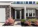 Charming home featuring a stone facade, black front door, landscaped garden bed, and a covered front porch at 804 S Pointe Blvd, Summerville, SC 29483