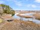 Stunning aerial view of the property's dock, surrounded by lush marshland and a tranquil creek at 12 Trachelle Ln, Charleston, SC 29407