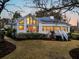 Back exterior of home featuring solar panels, expansive windows, and a well-manicured lawn at 12 Trachelle Ln, Charleston, SC 29407