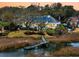 Charming waterfront home featuring a private dock, lush landscaping, and a serene setting at sunset at 12 Trachelle Ln, Charleston, SC 29407