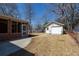 Backyard view featuring a brick sunroom, detached garage, concrete walkway, and grass lawn with bare trees at 1258 Redeemer Dr, Hanahan, SC 29410