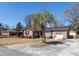 Charming red brick home featuring a one-car garage, well-manicured lawn, and complemented by a stately palm tree at 1258 Redeemer Dr, Hanahan, SC 29410