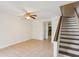 Bright living room featuring neutral tile flooring, staircase, ceiling fan and kitchen access at 1735 Boone Hall Dr # K14, Charleston, SC 29407