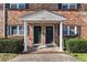 Charming brick exterior of townhome featuring covered entrance with dark doors and white columns at 1836 Mepkin Rd # D4, Charleston, SC 29407
