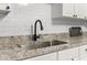 Close up of kitchen sink with granite counters, subway tile backsplash, and modern fixtures at 1836 Mepkin Rd # D4, Charleston, SC 29407