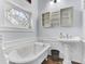 Bright bathroom features a clawfoot tub, pedestal sink, and unique window at 214 E Doty Ave, Summerville, SC 29483