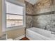 Bathroom showcasing a tiled shower-tub, window with waterfront view, and classic wooden flooring at 2399 Furman Dr, Charleston, SC 29414