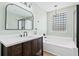 A modern bathroom features a bathtub with a glass block window, a black framed shower, and updated vanity at 2508 Melville Rd, North Charleston, SC 29406