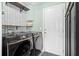 Modern laundry room features black front-load washer and dryer set, stylish wallpaper, and shelving at 2508 Melville Rd, North Charleston, SC 29406