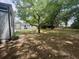 Large back yard with mature trees, a white house, shed, basketball hoop, and plenty of space for outdoor activities at 5273 Potomac St, North Charleston, SC 29405