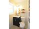 Compact bathroom features dark vanity with gold hardware, toilet, mirror, and shelves for decor at 5273 Potomac St, North Charleston, SC 29405