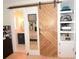 A hallway featuring a sliding barn door, built-in shelving, and a mirror with a glimpse of the bedroom and bathroom at 5273 Potomac St, North Charleston, SC 29405