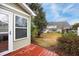 View of backyard with a red wood deck, green lawn, landscaping and neighboring homes in the background at 8618 Grassy Oak Trl, North Charleston, SC 29420