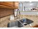 Close-up of a stainless steel kitchen sink with granite countertops and stylish mosaic backsplash at 8618 Grassy Oak Trl, North Charleston, SC 29420