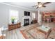 Open-concept living room with a fireplace, wood-look floors, and ample natural light at 8745 Alexandria Dr, North Charleston, SC 29420