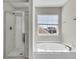 Bright bathroom featuring a glass enclosed shower, a soaking tub, and a window with neighborhood views at 105 Endicott Ct, Summerville, SC 29486