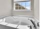 Close-up of a bright, white soaking tub with chrome fixtures and a window nearby at 105 Endicott Ct, Summerville, SC 29486