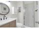 Well-lit bathroom featuring a glass shower, a wood vanity, and a round mirror at 1142 Village Creek Ln # 3, Mount Pleasant, SC 29464