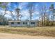 Well-maintained single-story home featuring gray siding, black shutters, and a welcoming front porch, nestled in nature at 116 Wisteria Falls Trl, Saint Stephen, SC 29479