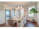 Elegant dining room with a white table, chandelier lighting, hardwood floors, and natural light from large windows at 1625 Oak Leaf St, Daniel Island, SC 29492