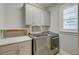Functional laundry room with modern washer and dryer, ample counter space, and storage cabinets at 1625 Oak Leaf St, Daniel Island, SC 29492