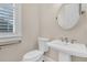 Charming powder room featuring a pedestal sink, round mirror, and window with plantation shutters at 2032 Amenity Park Dr, Mount Pleasant, SC 29466
