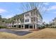 Elegant light gray home with multiple balconies surrounded by palm trees with a manicured lawn and inviting curb appeal at 2032 Amenity Park Dr, Mount Pleasant, SC 29466