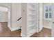 Hallway with hardwood floors, white trim, and a built-in bookshelf leading to a bathroom with window at 2032 Amenity Park Dr, Mount Pleasant, SC 29466