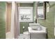 Stylish bathroom with green textured wallpaper, round sink, decorative mirror, and a shower with tan geometric tiles at 2115 Wappoo Dr, Charleston, SC 29412