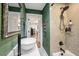 A stylish bathroom with grasscloth wallpaper, a modern white sink, a shower with geometric tiles, and an adjacent doorway at 2115 Wappoo Dr, Charleston, SC 29412