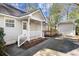 Charming home exterior with a covered porch, white railing, and a detached garage, nestled next to lush greenery at 25 Oak Forest Dr, Charleston, SC 29407