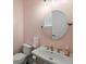 Stylish powder room with a round mirror, pedestal sink, and soft pink walls at 3003 Yachtsman Dr, Mount Pleasant, SC 29466