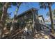 View of backyard with pump system, green home exterior, porch, and tropical trees at 3323 Myrtle St, Edisto Island, SC 29438