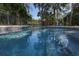 Close up view of blue backyard pool with a surrounding fence, trees, and clear blue sky at 3323 Myrtle St, Edisto Island, SC 29438