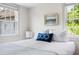 Sunlit bedroom with white linens, blue accent pillow and large windows providing exterior views at 5 Alexander St, Charleston, SC 29401
