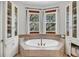Luxurious bathroom featuring a large soaking tub, built-in storage, and natural light from two large windows at 6021 Jibe Ct, Awendaw, SC 29429