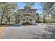 Charming home with a welcoming front porch, double garages, and a gravel driveway surrounded by mature trees at 6021 Jibe Ct, Awendaw, SC 29429
