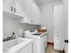 Well-lit laundry room featuring modern washer and dryer, white cabinetry, and basin sink at 6021 Jibe Ct, Awendaw, SC 29429