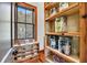 Organized pantry features wooden shelves stocked with various food items and natural light from a window at 6021 Jibe Ct, Awendaw, SC 29429