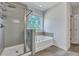 Bright bathroom features a tiled shower, soaking tub beneath a window, and neutral color palette at 130 Wappoo Trace Ln, Summerville, SC 29486