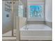 Bright bathroom features a tiled shower, a soaking tub beneath a window, and neutral color palette at 130 Wappoo Trace Ln, Summerville, SC 29486