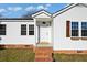 Close-up of the charming white-sided house entrance with a brick porch, windows, and decorative shutters at 1409 Main St, Bonneau, SC 29431