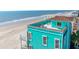 Aerial view showcasing the teal beach house with a rooftop deck, situated right on the sandy shoreline at 1699 E Ashley Ave # B, Folly Beach, SC 29439