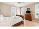 Bedroom with wood floors, ceiling fan, two windows, and a TV on top of a wooden dresser at 1699 E Ashley Ave # B, Folly Beach, SC 29439