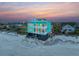 Beachfront home with a turquoise exterior, multiple stories, and stunning ocean views at sunset at 1699 E Ashley Ave # B, Folly Beach, SC 29439