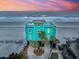 Beachfront home with a turquoise exterior, multiple stories, and stunning ocean views at sunset at 1699 E Ashley Ave # B, Folly Beach, SC 29439